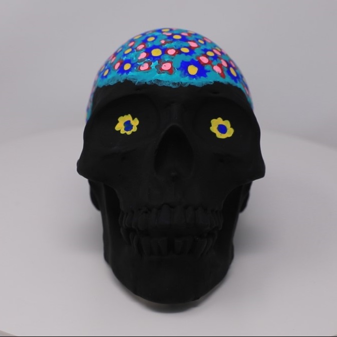 Black Matte painted skull with a blue painted head with flower details on the head and in the eyes.
